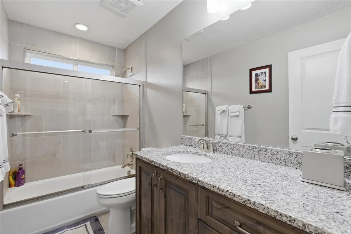 Bathroom featuring a single vanity with a granite countertop, undermount sink, and dark wood-finish cabinetry