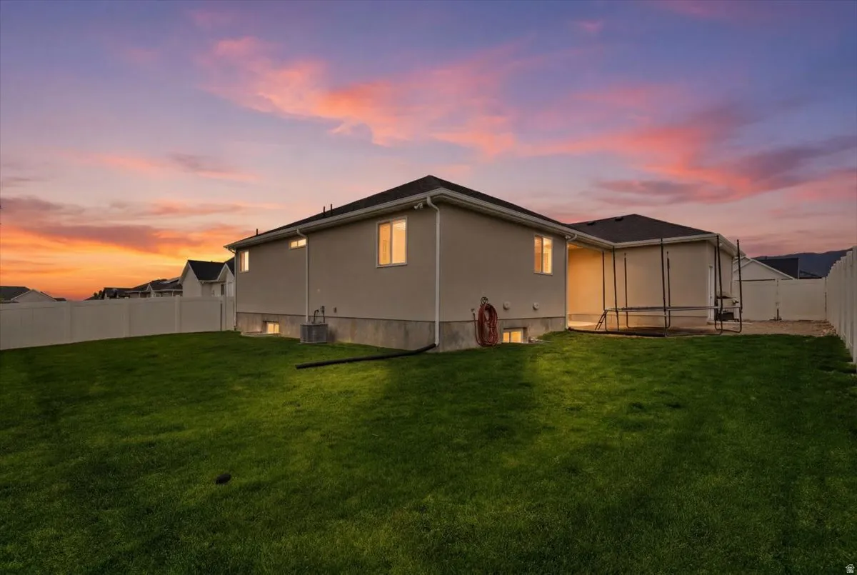Expansive rear yard featuring a manicured lawn, full perimeter fencing, and a stucco exterior