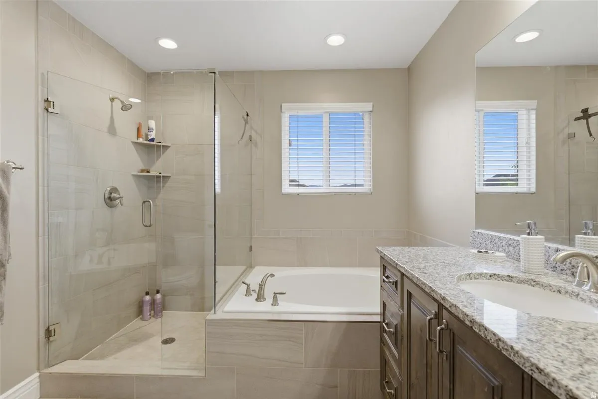 Contemporary bathroom featuring a glass-enclosed shower with tile surround and built-in shelving, a separate soaking tub, and a double vanity with stone countertop and integrated sink