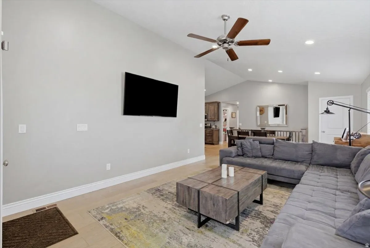 Open concept living space featuring vaulted ceilings with a ceiling fan, recessed lighting, and wood-finish flooring