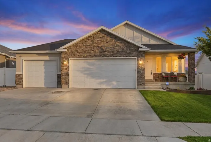 Exterior featuring a stone and siding facade, covered front porch, and a three-car garage with individual doors