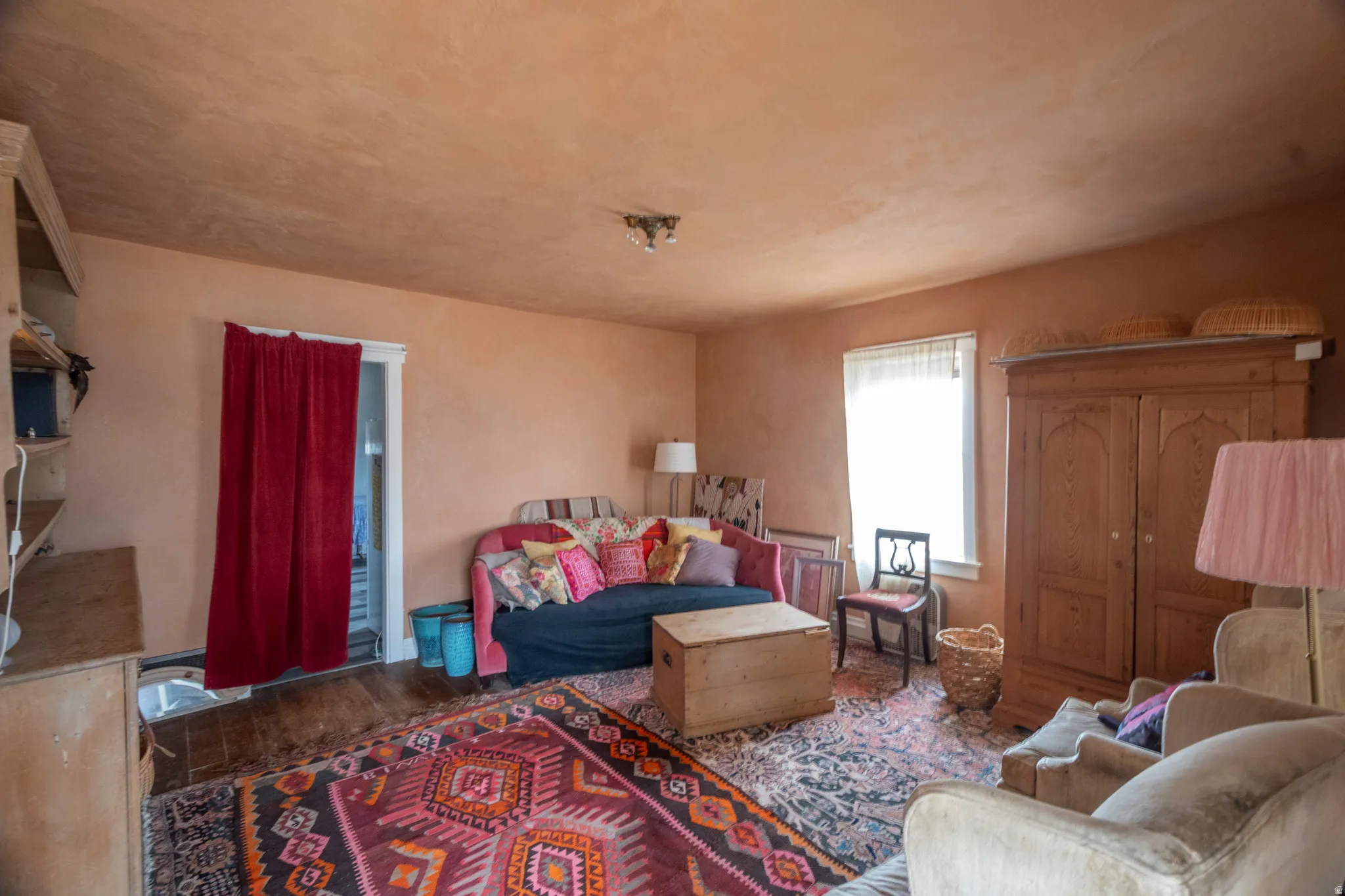 Spacious room featuring wood-finish flooring, a bright window, and a built-in shelving unit