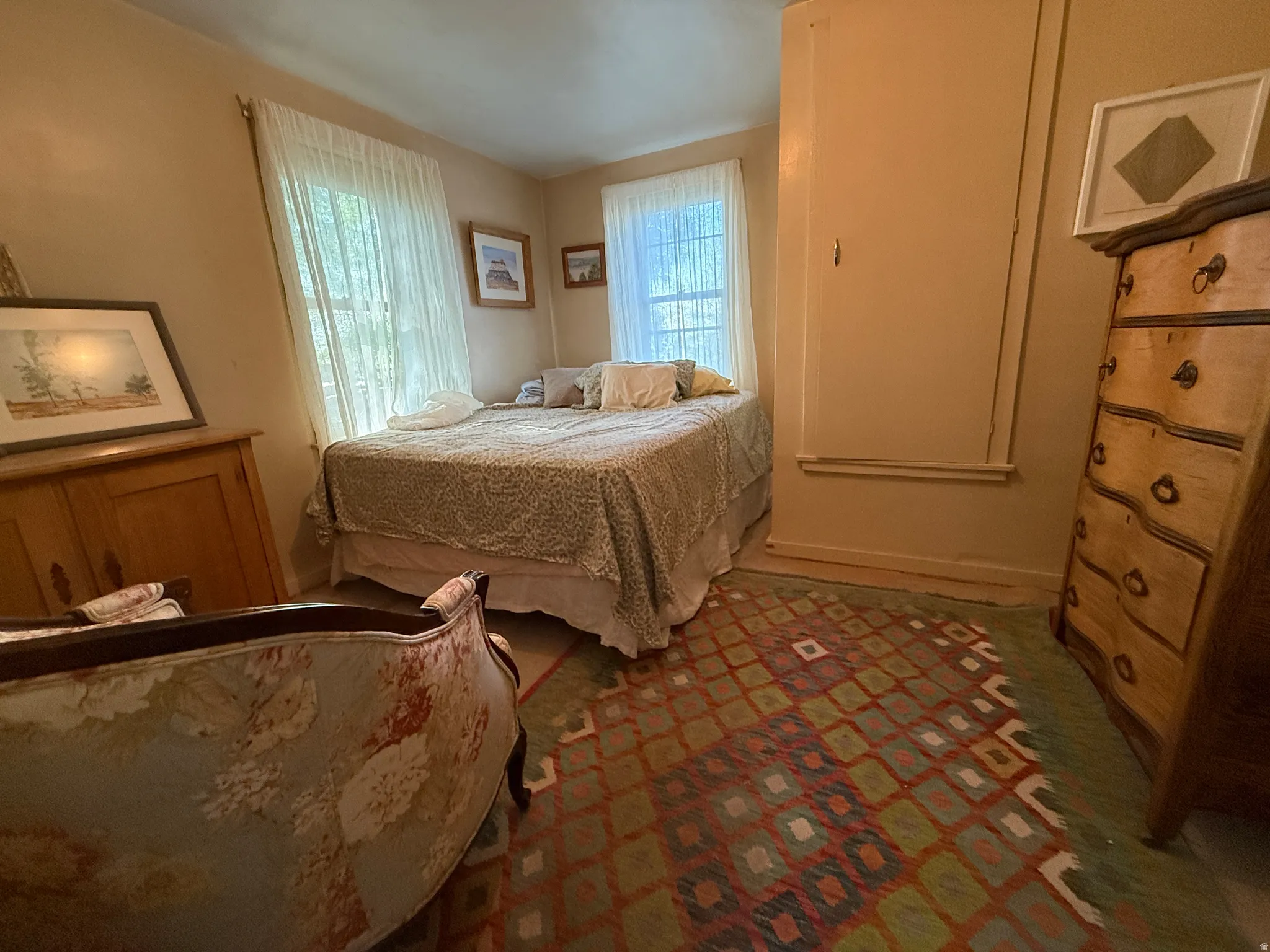 Room featuring neutral wall tones, two windows with sheer coverings, and a built-in storage cabinet