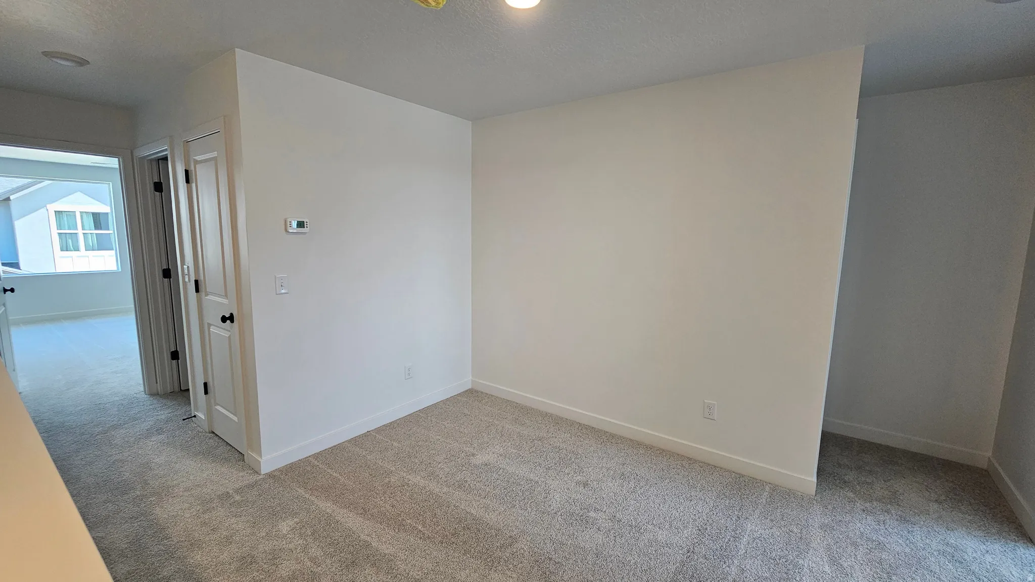 Carpeted interior space featuring white walls and baseboards
