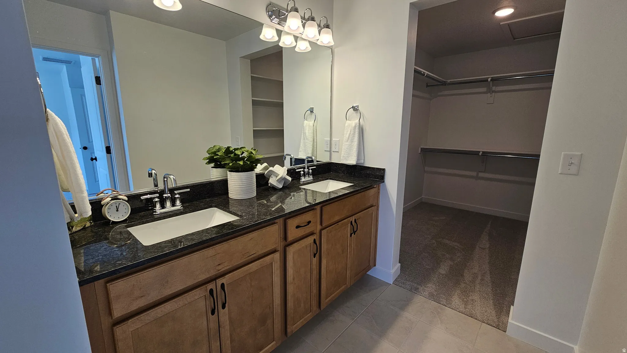 Dual vanity featuring wood-finish cabinetry and a dark stone countertop with undermount sinks