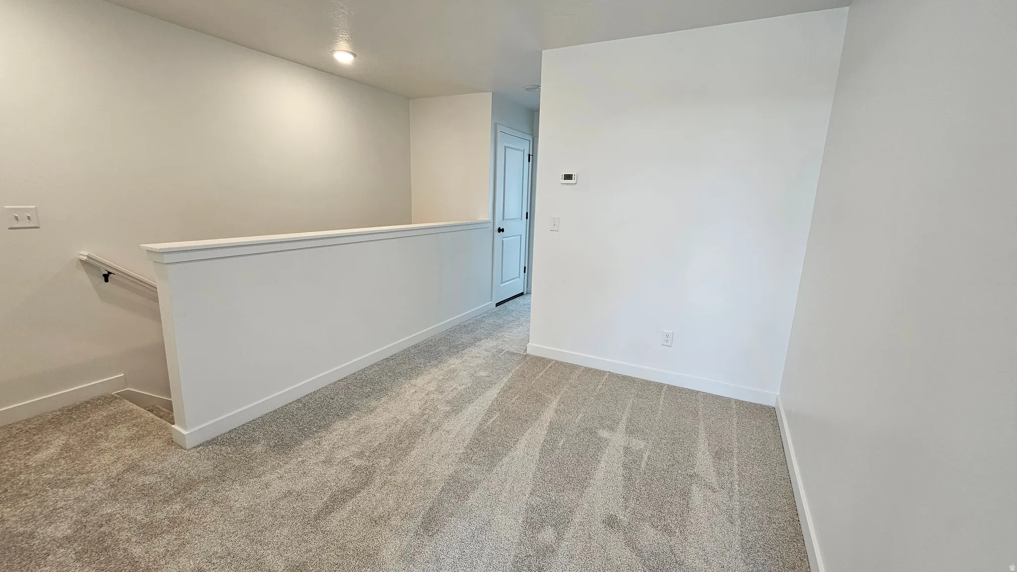 Upper-level landing featuring neutral-toned carpet, white walls, and recessed lighting
