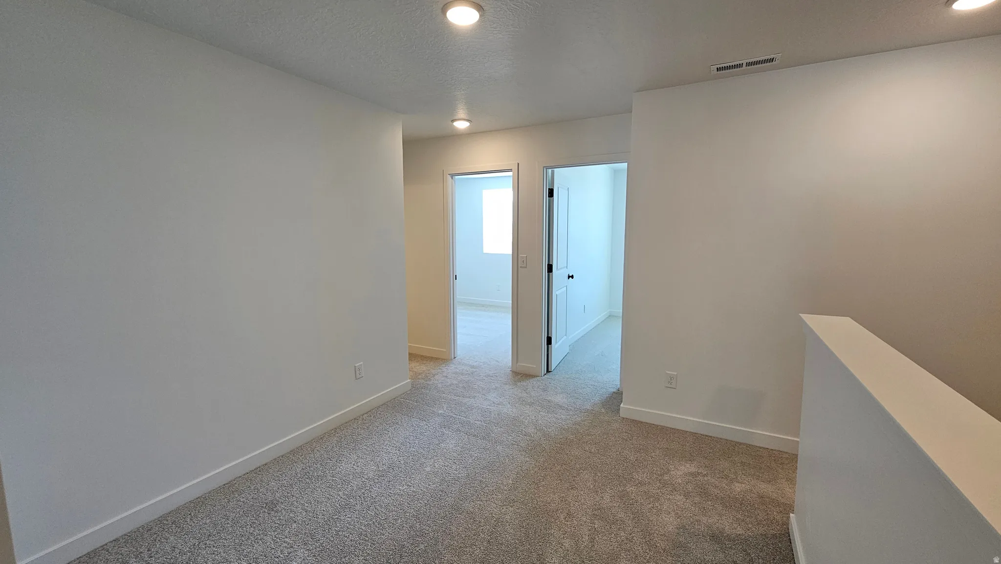 Carpeted hallway with recessed lighting and light-colored walls