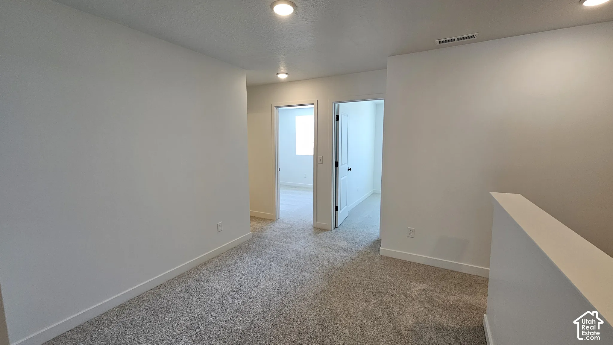 Carpeted hallway with recessed lighting and light-colored walls