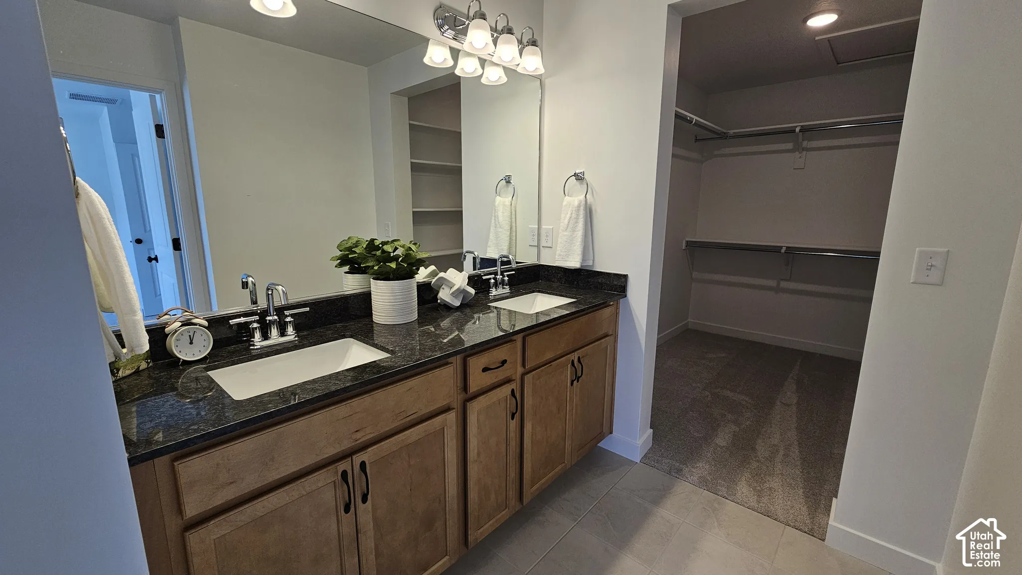 Dual vanity featuring wood-finish cabinetry and a dark stone countertop with undermount sinks