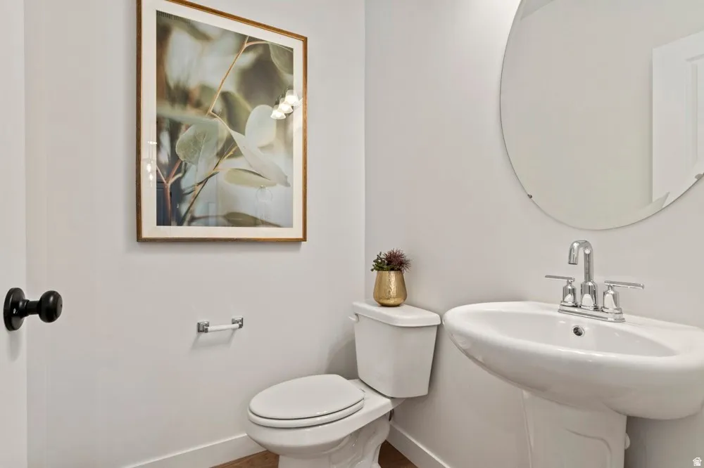 Pedestal sink with chrome faucet, complemented by a contemporary round mirror