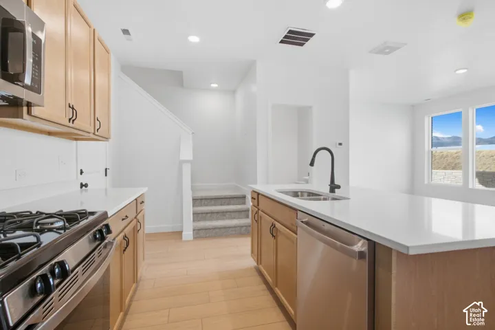 Kitchen featuring natural wood-finish cabinetry, quartz countertops, a stainless steel range, and a matte black faucet