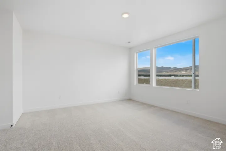 Neutral-toned carpeting, recessed ceiling lighting, and expansive windows featuring mountain scenery