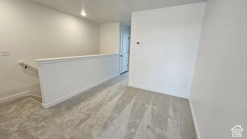 Upper-level landing featuring neutral-toned carpet, white walls, and recessed lighting