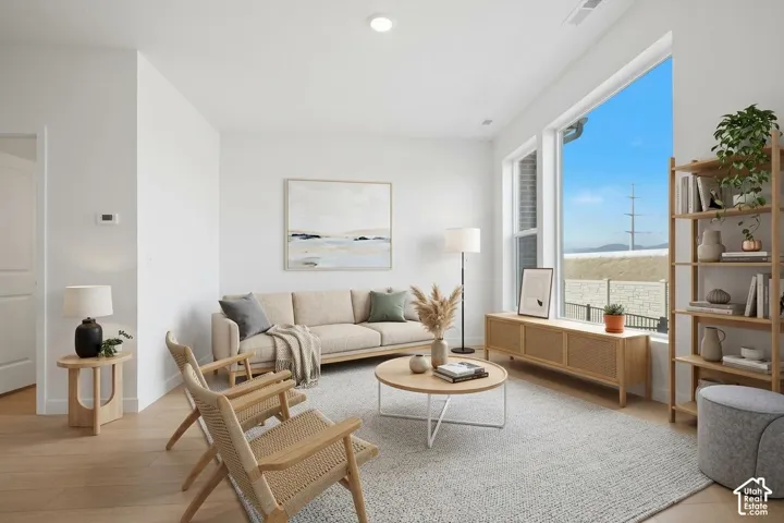 Living area featuring high ceilings, neutral wall tones, wood-finish flooring, and expansive windows