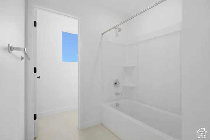 Bathtub and shower combination with a molded surround, integrated soap shelving, chrome fixtures, and a polished metal shower rod