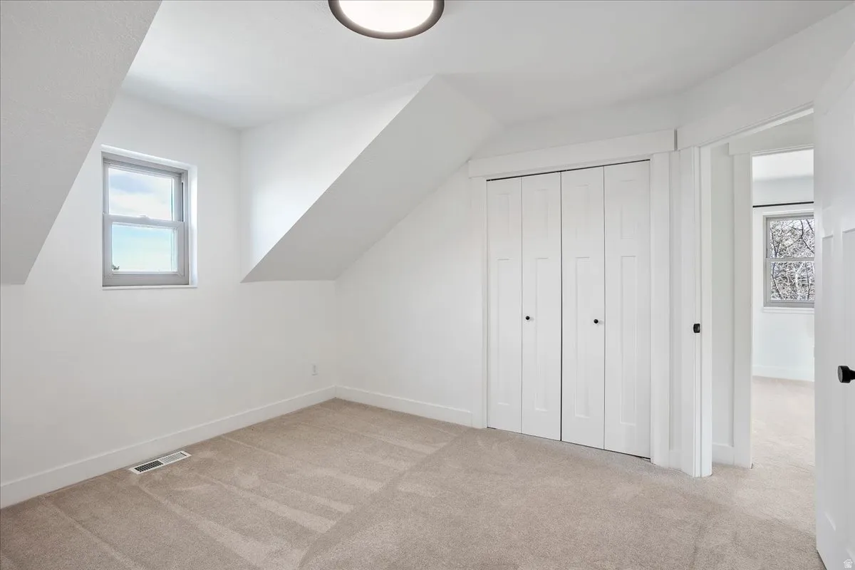 Carpeted room with a double bi-fold closet, a single window, and a flush-mount ceiling light fixture