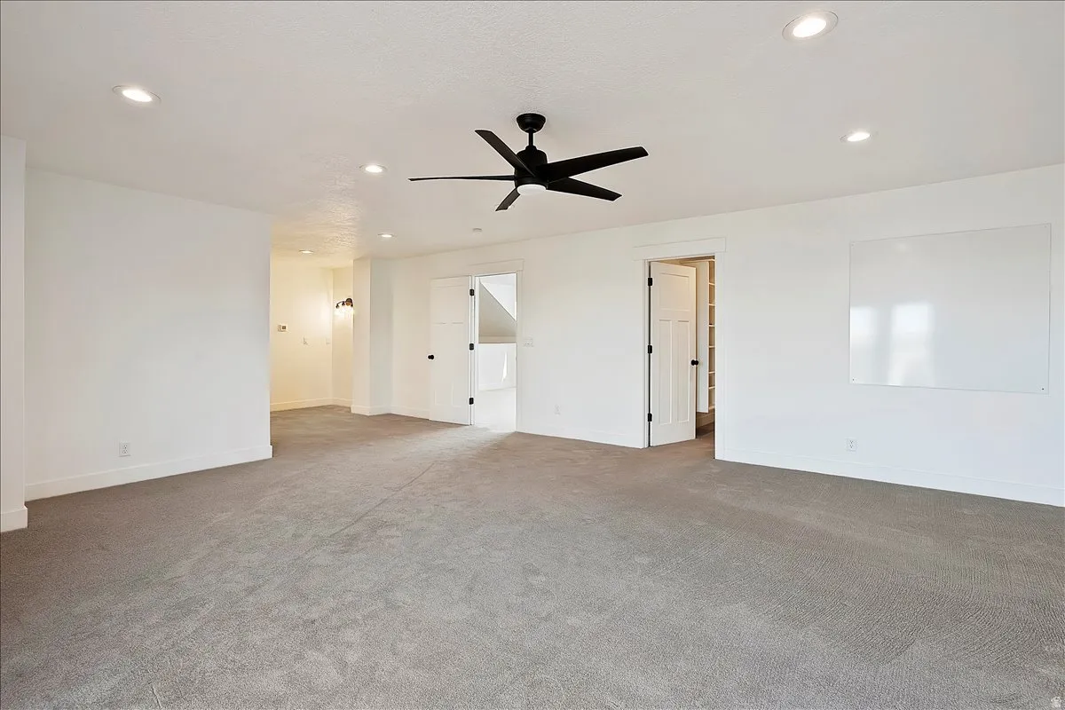 Spacious room featuring neutral carpeting, recessed lighting, and a contemporary ceiling fan