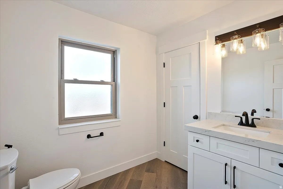 Bathroom featuring a single vanity with white cabinetry, a light-toned countertop, and a rectangular undermount sink with a matte black faucet