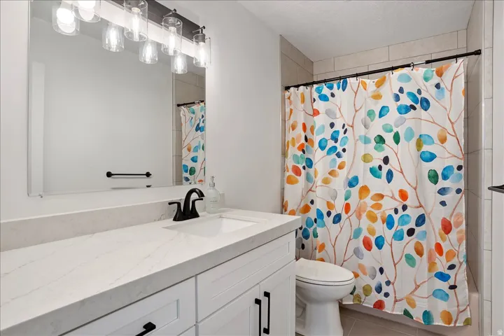 Bathroom featuring a white vanity with an integrated sink, quartz-finish countertop, and matte black fixtures