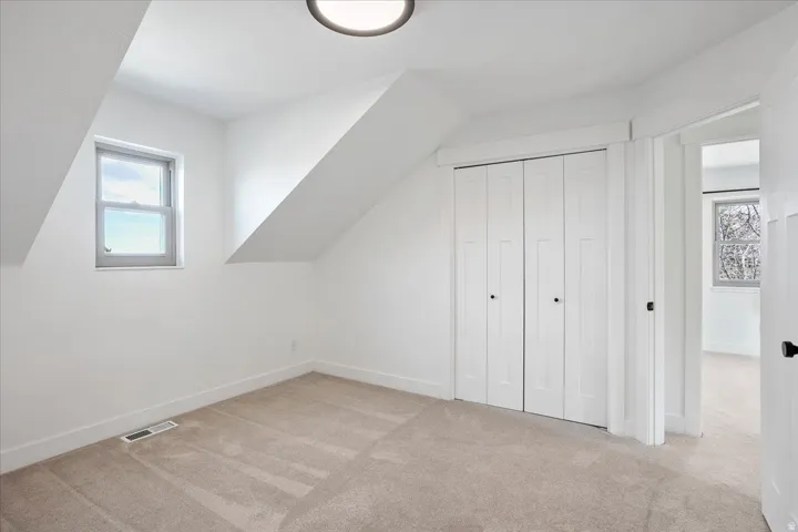 Carpeted room with a double bi-fold closet, a single window, and a flush-mount ceiling light fixture