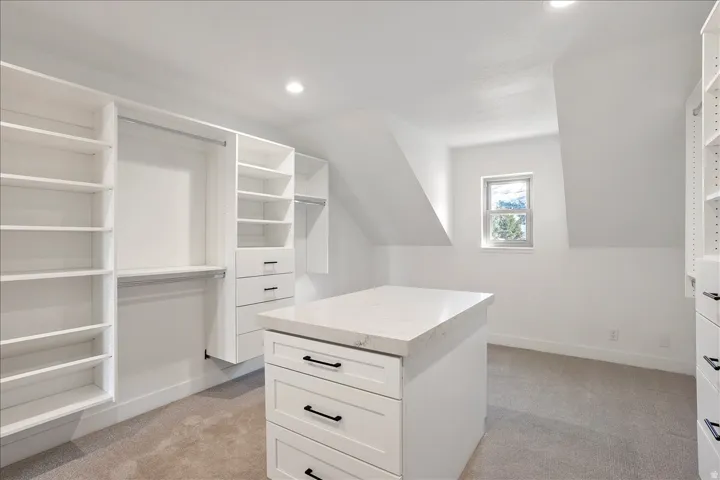 Custom closet system featuring white cabinetry, built-in shelving, and hanging rods