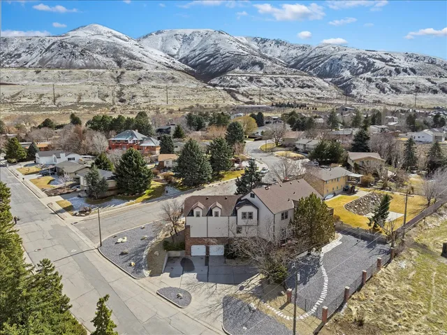 Elevated property with a multi-level structure featuring a two-car garage and a stone-chip driveway