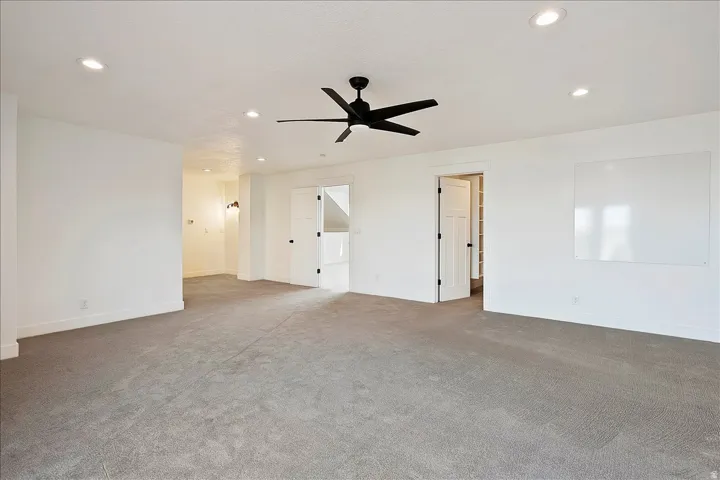 Spacious room featuring neutral carpeting, recessed lighting, and a contemporary ceiling fan
