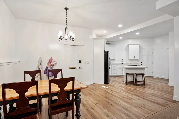 Open-concept living space featuring wood-finish flooring throughout, a modern kitchen with white cabinetry, and recessed lighting