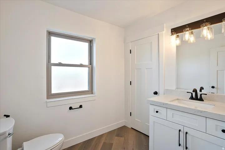 Bathroom featuring a single vanity with white cabinetry, a light-toned countertop, and a rectangular undermount sink with a matte black faucet