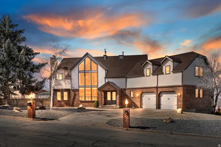 Stately residence featuring a prominent two-story window array, brick accents, and a two-car garage