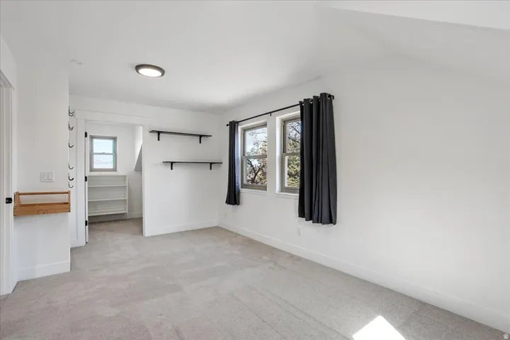 Carpeted room with a flush-mount ceiling light and two windows