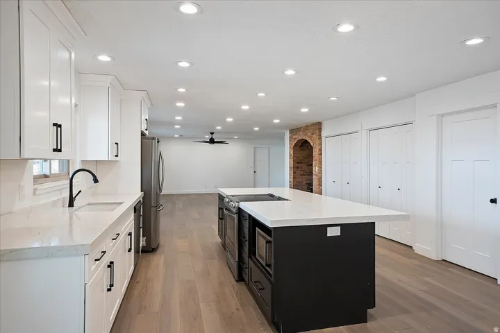 Spacious kitchen featuring an expansive island, white cabinetry with matte black hardware, stainless steel appliances, and recessed lighting