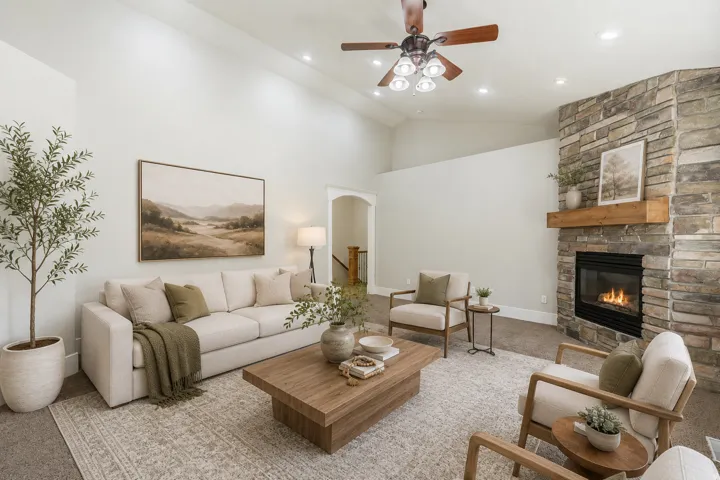 Vaulted ceiling living space featuring a stone-clad fireplace with a wood mantle, recessed lighting, and a ceiling fan