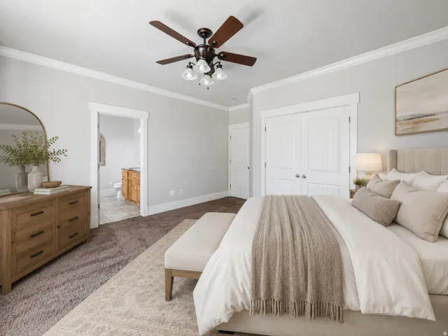 Owner's suite featuring neutral carpeting, white trim work, a ceiling fan with integrated lighting, and double-door closet access