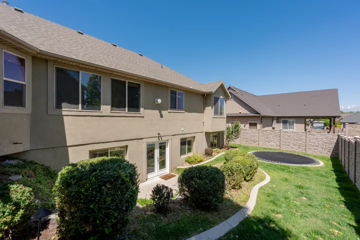 Expansive backyard featuring a manicured lawn, established landscaping, and a privacy fence