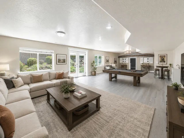Spacious recreation room featuring light wood-finish flooring, recessed lighting, and multiple windows