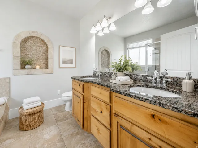 Owner's Bathroom featuring a double vanity with stone countertops, integrated sinks, and wood cabinetry