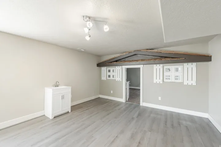 Open room featuring wood-finish flooring, a white vanity with a sink, and track lighting