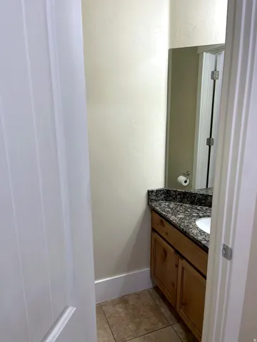 Compact bathroom featuring a wood-finish vanity with a granite countertop and an integrated sink