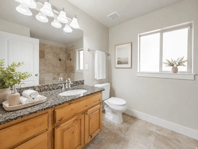 Bathroom featuring a wooden vanity with a granite countertop, undermount sink, and chrome faucet