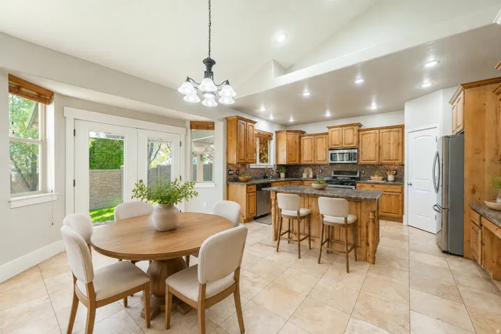 Kitchen featuring natural wood cabinetry, stone countertops, a central island with bar seating, and stainless steel appliances