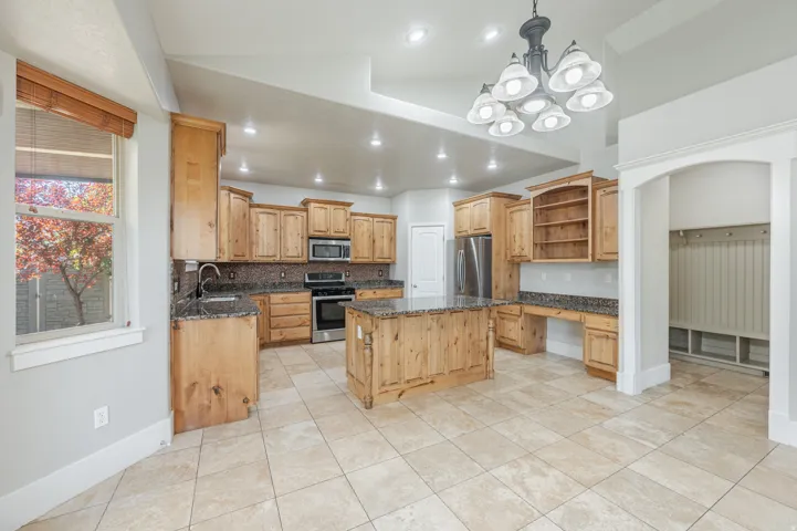 Spacious kitchen featuring natural wood cabinetry, granite countertops, stainless steel appliances, and a central island