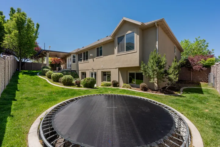Expansive backyard featuring a manicured lawn, tiered landscaping, and mature trees