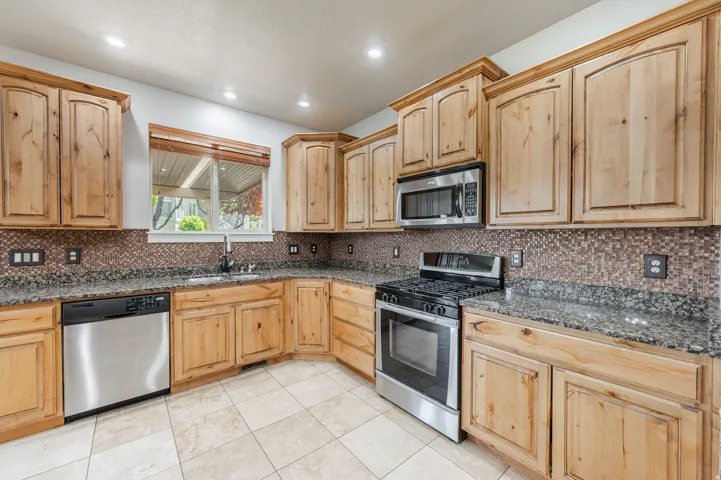Kitchen featuring wood cabinetry, granite-finish countertops, and a mosaic tile backsplash