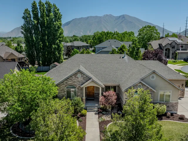 Stone and stucco exterior residence featuring a gray asphalt shingle roof