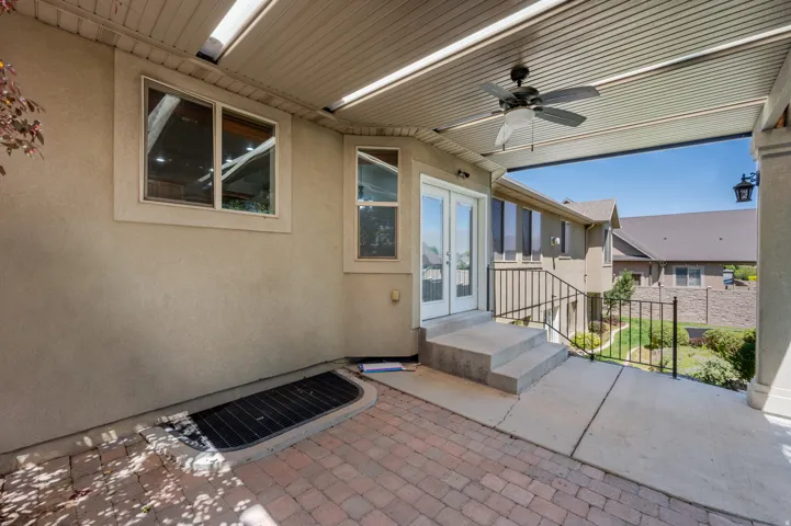 Covered patio featuring a ceiling fan, dual light fixtures, and a recessed slatted ceiling