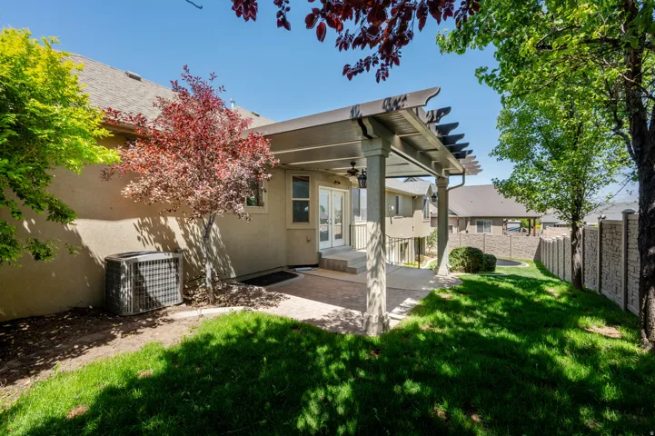 Stucco exterior with a covered patio featuring a pergola, dual ceiling fans, and concrete columns