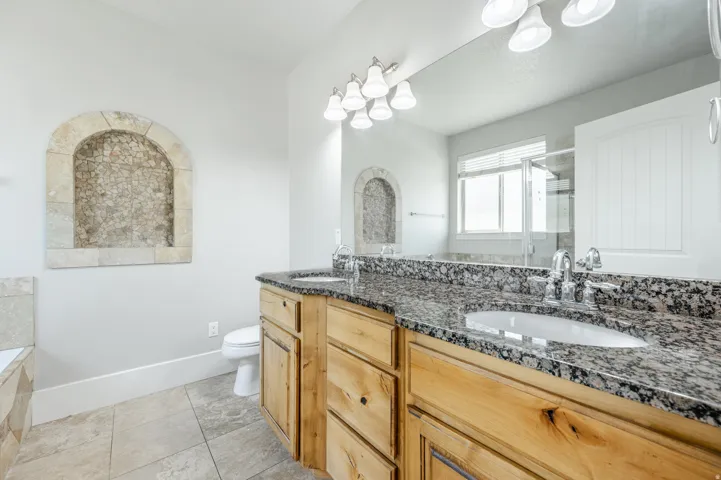 Dual vanity with granite countertops, undermount sinks, and natural wood cabinetry