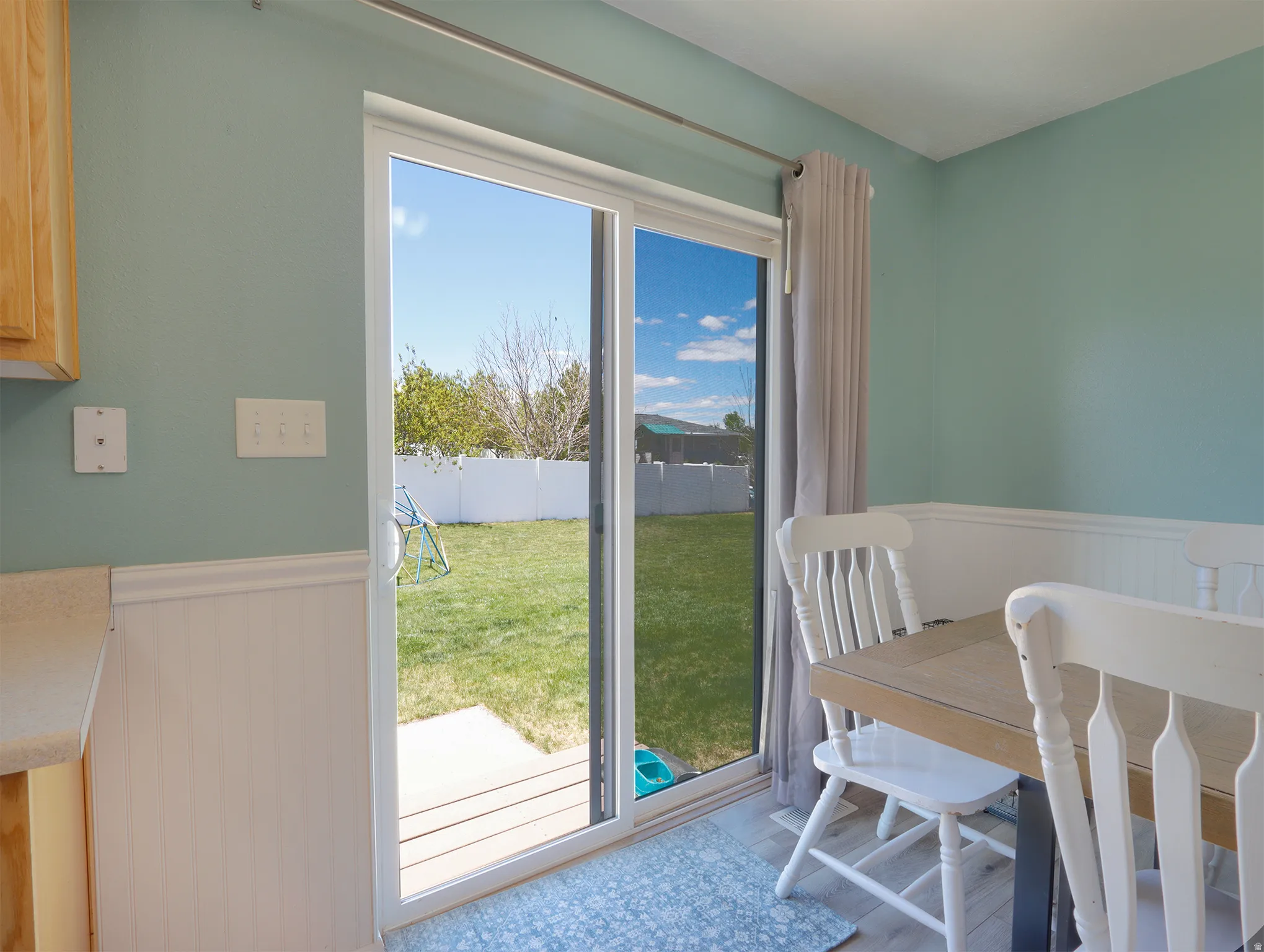 Sliding glass door opening to a fully fenced backyard with a grass lawn and a concrete patio
