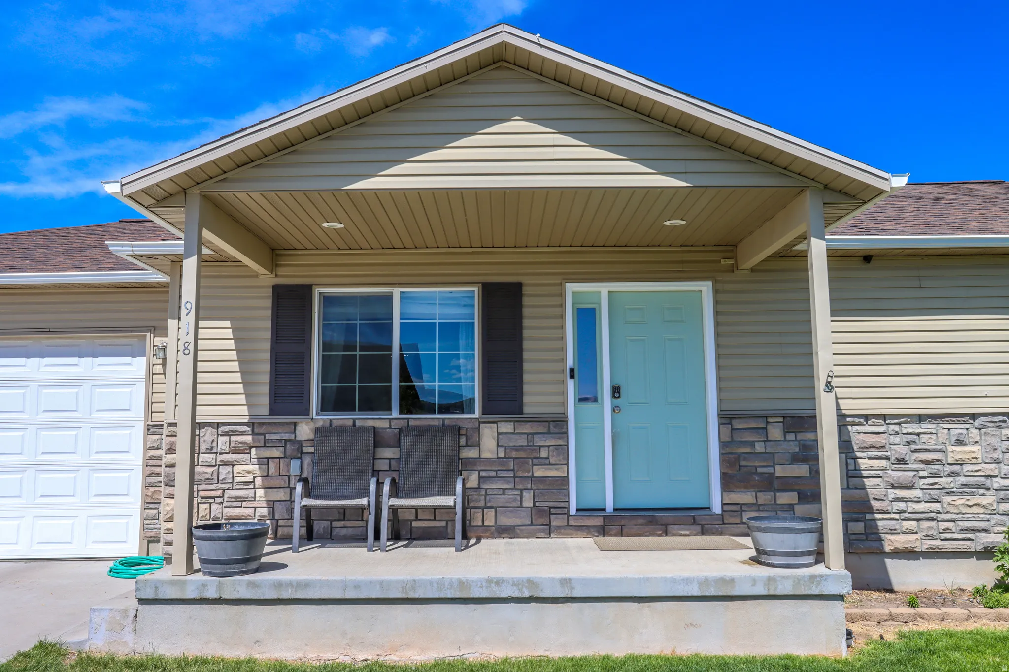 Property exterior featuring stone veneer accents, light beige siding, and a covered porch